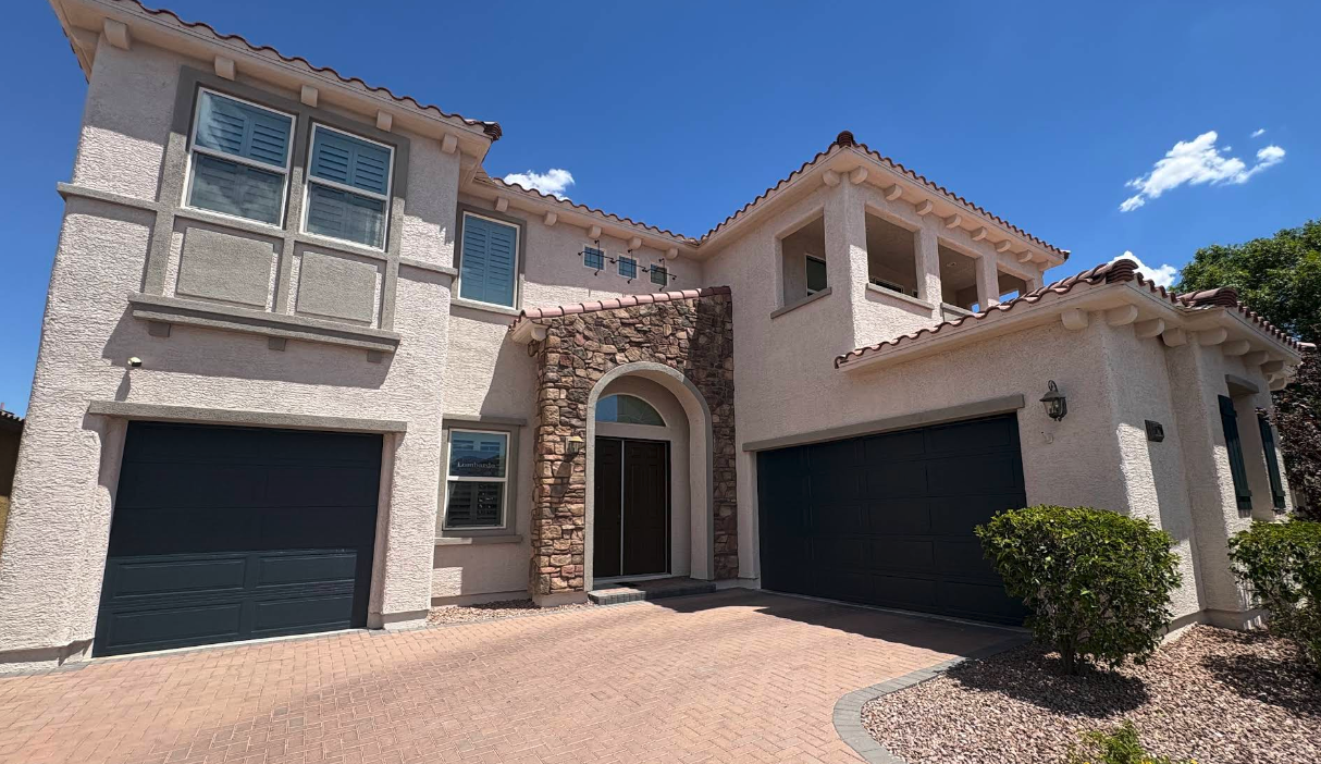 Two-story stucco home with freshly painted exterior and dark garage doors